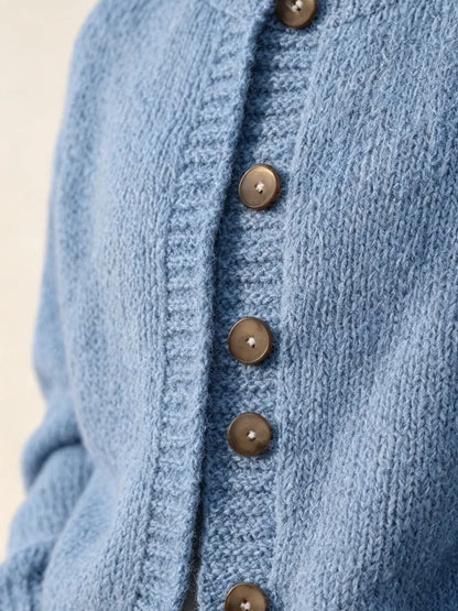 The women's smog-blue solid-color knitted cardigan is made of thick knitted fabric. It has a round neck and front buttons. It is suitable for wearing in autumn and winter, has strong versatility, and has a slightly European-s
