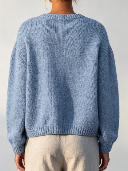 The women's smog-blue solid-color knitted cardigan is made of thick knitted fabric. It has a round neck and front buttons. It is suitable for wearing in autumn and winter, has strong versatility, and has a slightly European-s
