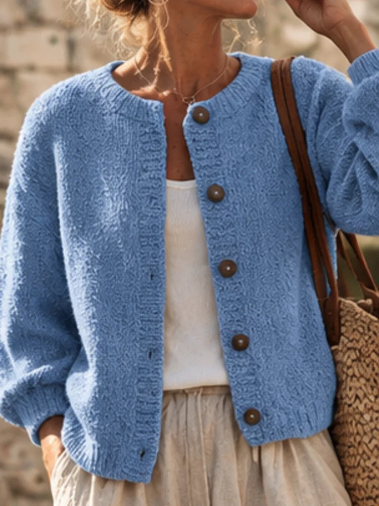 The women's smog-blue solid-color knitted cardigan is made of thick knitted fabric. It has a round neck and front buttons. It is suitable for wearing in autumn and winter, has strong versatility, and has a slightly European-s