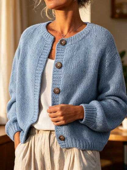 The women's smog-blue solid-color knitted cardigan is made of thick knitted fabric. It has a round neck and front buttons. It is suitable for wearing in autumn and winter, has strong versatility, and has a slightly European-s