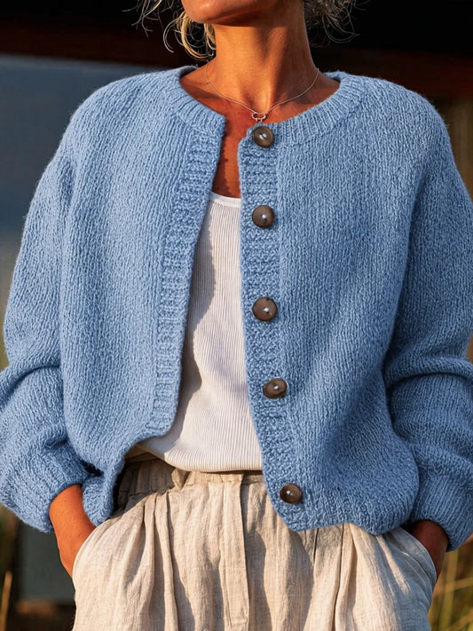The women's smog-blue solid-color knitted cardigan is made of thick knitted fabric. It has a round neck and front buttons. It is suitable for wearing in autumn and winter, has strong versatility, and has a slightly European-s