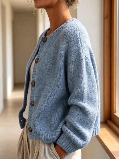 The women's smog-blue solid-color knitted cardigan is made of thick knitted fabric. It has a round neck and front buttons. It is suitable for wearing in autumn and winter, has strong versatility, and has a slightly European-s