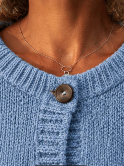 The women's smog-blue solid-color knitted cardigan is made of thick knitted fabric. It has a round neck and front buttons. It is suitable for wearing in autumn and winter, has strong versatility, and has a slightly European-s